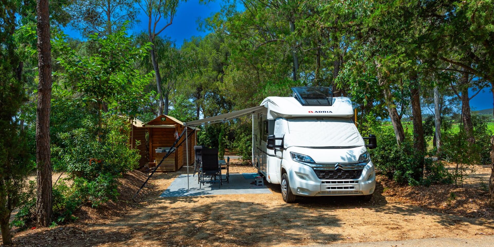 Caravan pitch with private sanitary facilities in tree-filled campsite